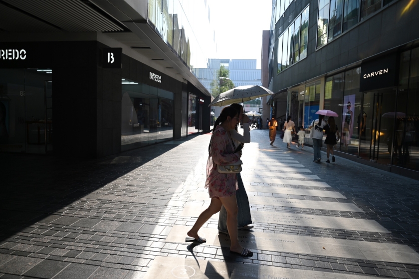 Une femme traverse une rue de la ville par des températures élevées.
