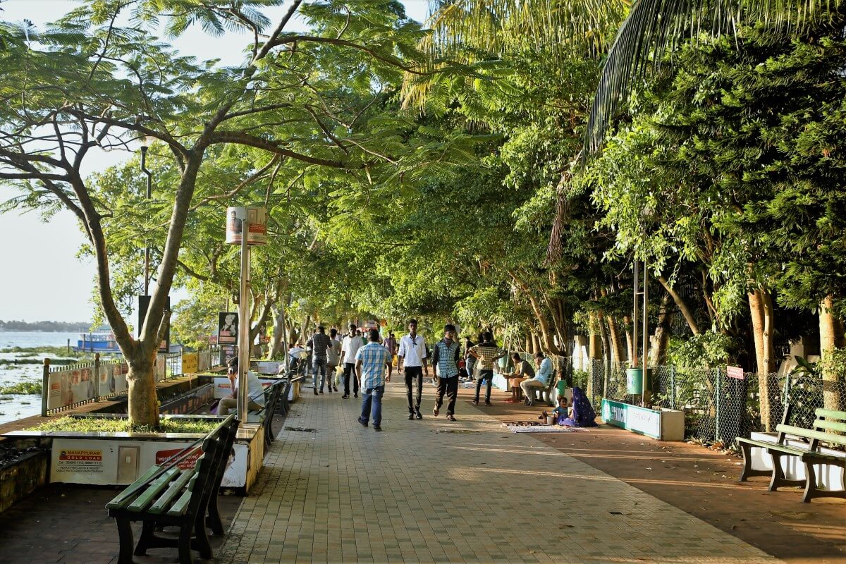 Photographie de Marine Drive à Kochi ; les gens marchent sous les arbres.