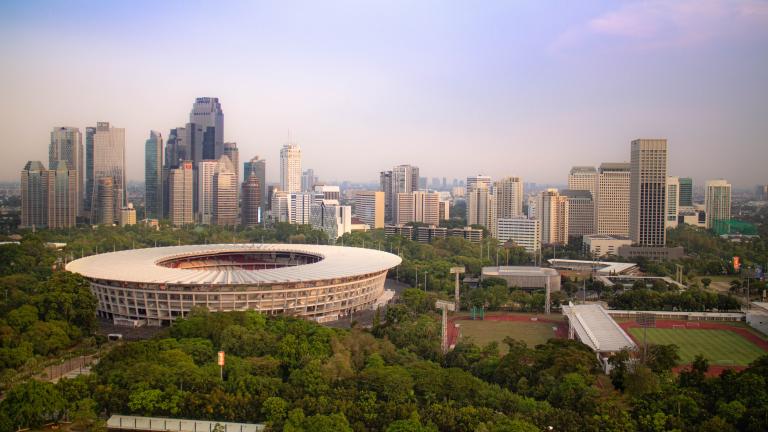 Vue du stade Gelora Bung Karno à Jakarta, entouré d'arbres et de la ligne d'horizon de la ville.