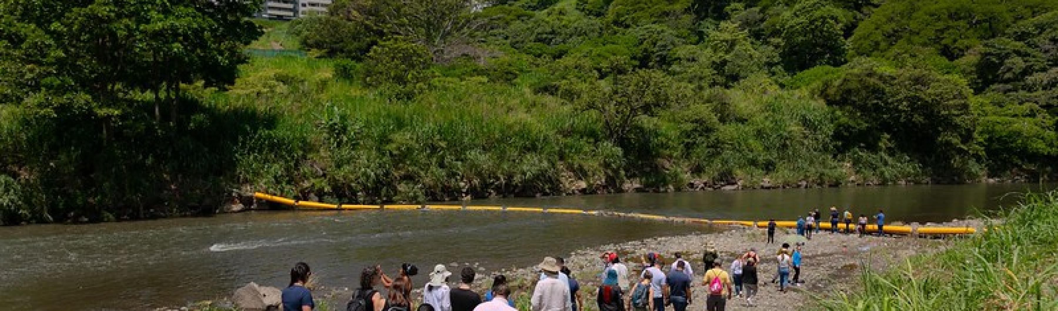 Les participants à la Costa Rica City Academy marchent sur les rives de la rivière Virilla pour voir la barrière de plastique qui retient les déchets.