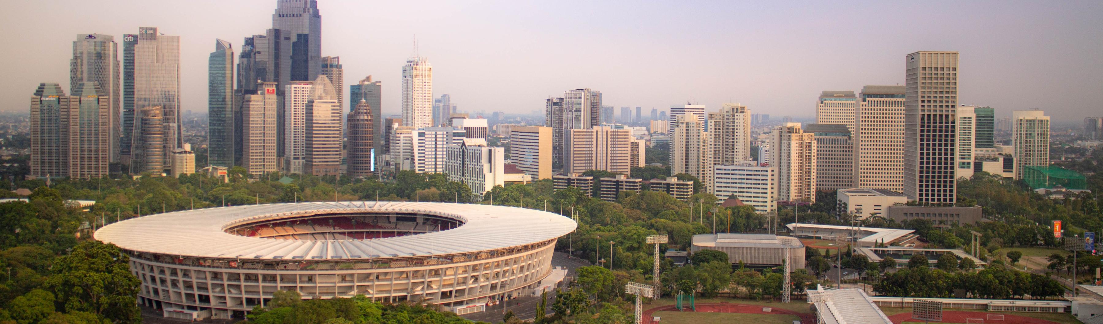 Vue du stade Gelora Bung Karno à Jakarta, entouré d'arbres et de la ligne d'horizon de la ville.